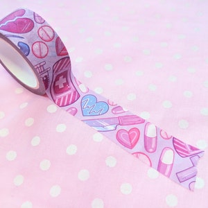May include: A roll of pink washi tape with a pattern of hearts, pills, and medical symbols. The tape is on a pink background with white polka dots.