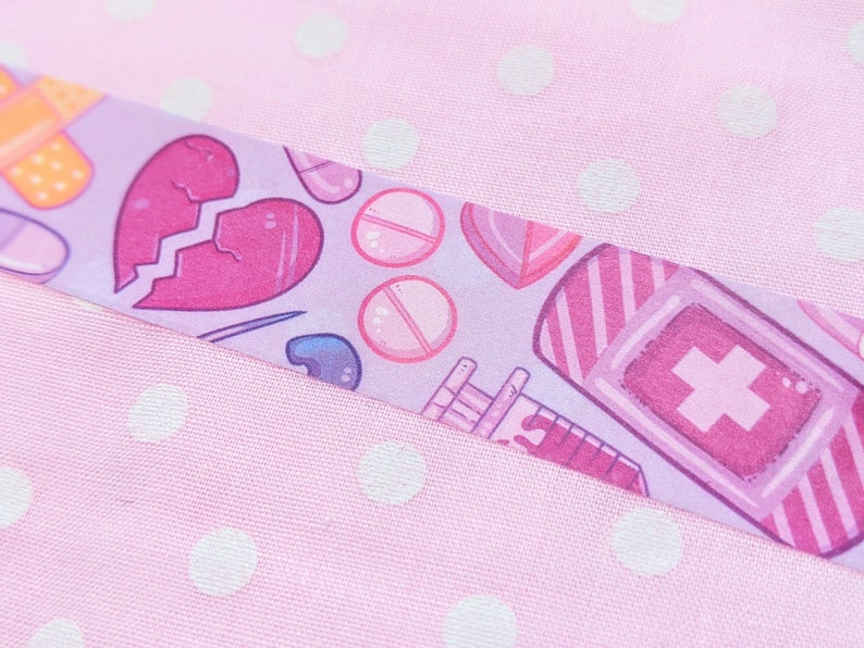 May include: A purple and pink patterned washi tape with a broken heart, pills, bandages, and a bottle with a cross on it.
