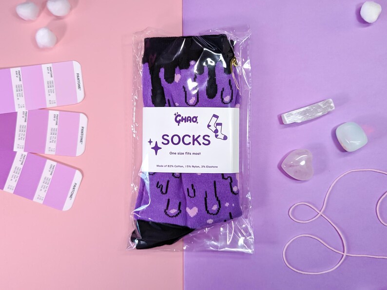 May include: Purple and black socks with a dripping ice cream cone design. The socks are packaged in a clear plastic bag with a white label that reads "Ghaa Socks" and "One size fits most".