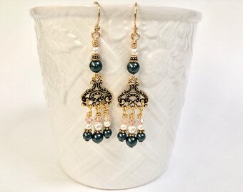 May include: Gold dangle earrings with a black and white bead design. The earrings feature a filigree charm and a drop of black, white, and pink beads.