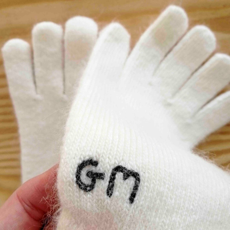 Puede incluir: Guantes de punto blancos con un logotipo "GM" negro en la mu&ntilde;eca.