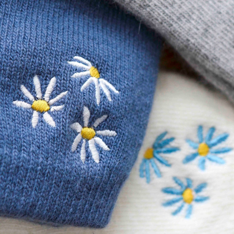 K&ouml;nnte beinhalten: Zwei Paar Socken mit gestickten G&auml;nsebl&uuml;mchen. Ein Paar ist blau mit wei&szlig;en G&auml;nsebl&uuml;mchen und das andere Paar ist wei&szlig; mit blauen G&auml;nsebl&uuml;mchen.