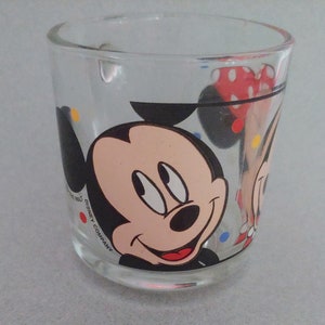 May include: A clear glass mug with a colorful polka dot pattern and a cartoon image of Mickey Mouse and Minnie Mouse. The mug has the text "DISNEY COMPANY" printed on the side.