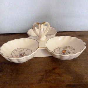 May include: A white ceramic three-section serving dish with a gold handle and floral design.