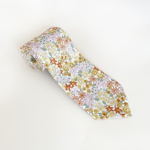 May include: A rolled-up necktie with a floral pattern. The tie features a white background with small flowers in shades of yellow, pink, and orange. The tie is made of a soft fabric and is suitable for formal or casual wear.