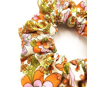 A retro floral scrunchie with a warm color palette and vintage-inspired design.