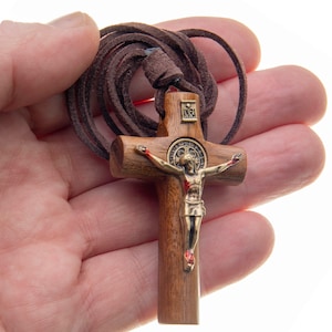 Pode incluir: Um crucifixo de madeira com um cord&atilde;o de couro castanho. O crucifixo apresenta uma figura de metal de Jesus Cristo com a inscri&ccedil;&atilde;o "INRI" na cruz.