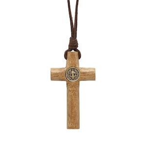 Pode incluir: Um colar com uma cruz de madeira e um cord&atilde;o de couro marrom. A cruz tem um pequeno medalh&atilde;o de metal no centro.