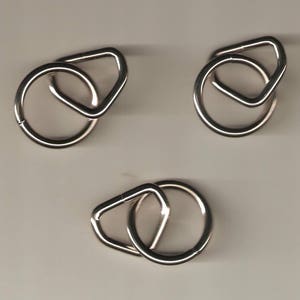 May include: Three silver metal key rings with a D-shaped ring and a smaller triangular ring.