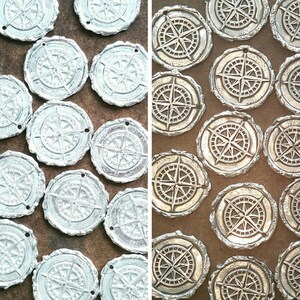 May include: Two rows of silver and gold compass charms with a detailed design. The charms are arranged in a grid pattern.