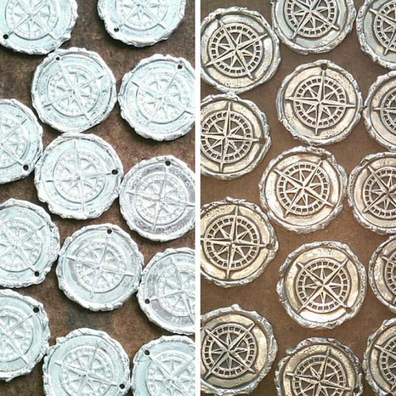 May include: Two rows of silver and gold compass charms with a detailed design. The charms are arranged in a grid pattern.