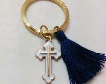 May include: Gold key chain with a white cross charm and a dark blue tassel.