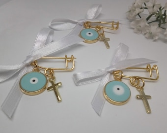 May include: Three gold safety pins with white satin ribbon bows. Each pin has a blue evil eye charm and a gold cross charm.