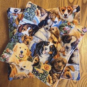 May include: Three quilted pot holders with a patchwork design featuring various dog breeds, including golden retrievers, corgis, and Bernese Mountain Dogs. The pot holders have a floral and dog-themed pattern with a white border.