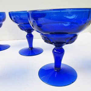 May include: Set of three cobalt blue glass stemmed cocktail glasses. The glasses have a fluted design and a wide bowl.