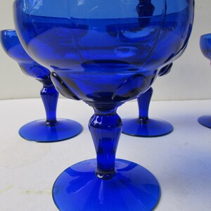 May include: Set of four cobalt blue glass stemmed dessert cups. The cups have a fluted design and a round base.