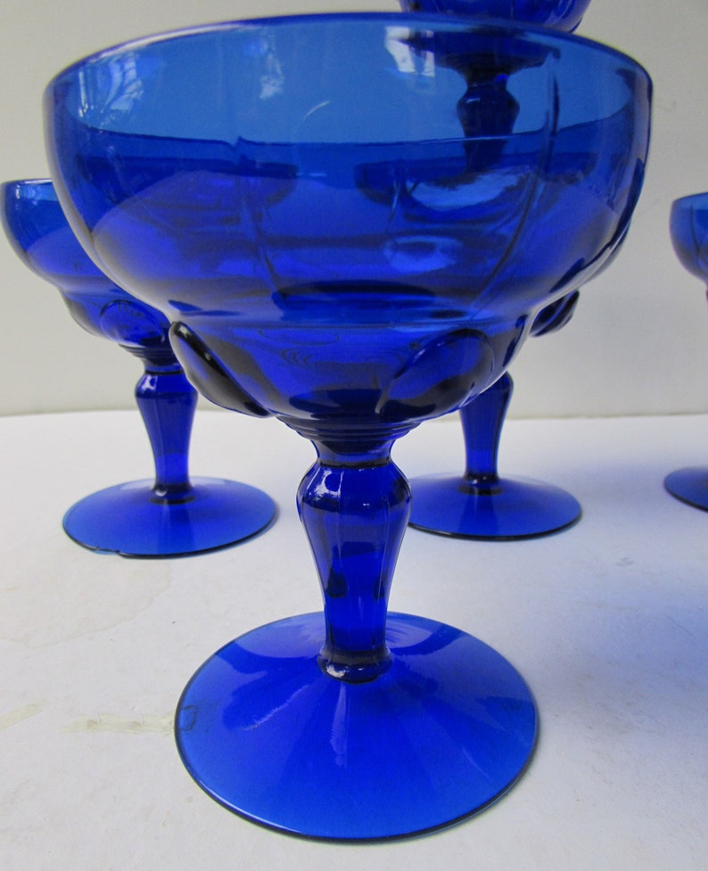 May include: Set of four cobalt blue glass stemmed dessert cups. The cups have a fluted design and a round base.
