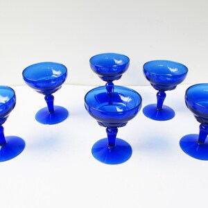 May include: Set of six cobalt blue glass champagne coupes with a fluted design.