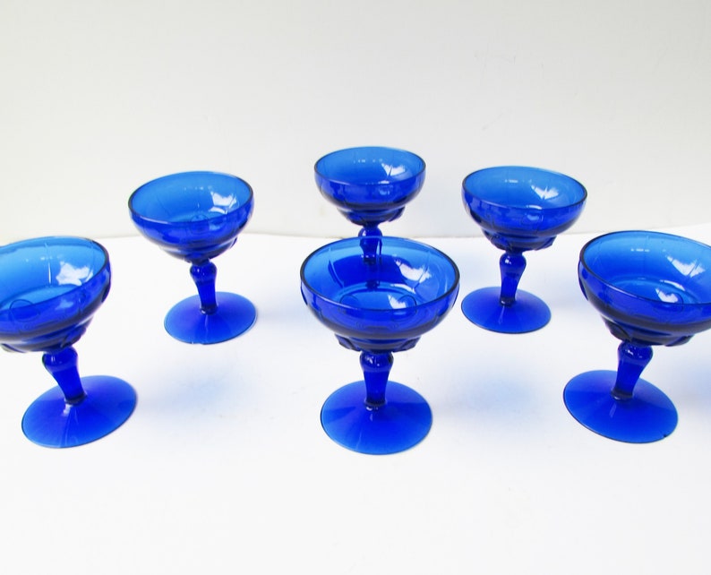 May include: Set of six cobalt blue glass champagne coupes with a fluted design.