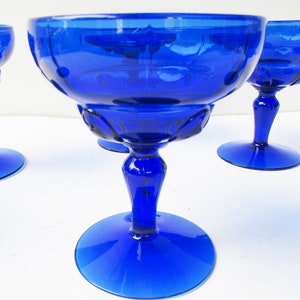May include: Set of four cobalt blue glass stemmed dessert cups. The cups have a fluted design and a wide, round base.