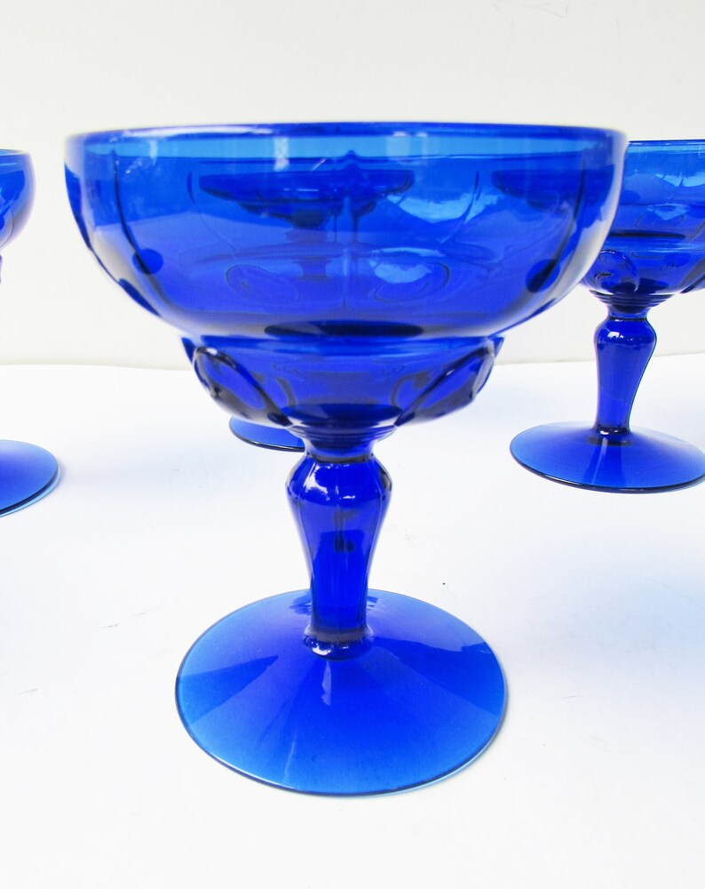 May include: Set of four cobalt blue glass stemmed dessert cups. The cups have a fluted design and a wide, round base.