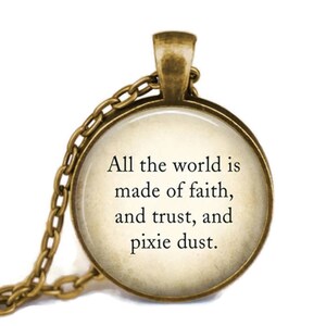 May include: A gold necklace with a round glass pendant featuring a quote: "All the world is made of faith, and trust, and pixie dust."