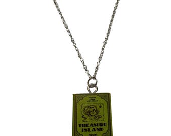 May include: A silver-toned chain necklace with a pendant shaped like a small green book. The book pendant features the title "TREASURE ISLAND" and a map illustration. The necklace is a literary-themed accessory.