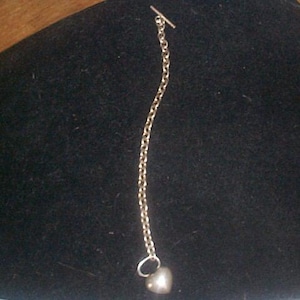 May include: A silver chain necklace with a heart-shaped pendant.