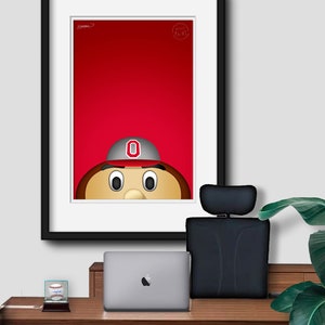 May include: A framed illustration of a cartoon mascot with a red background. The mascot is wearing a grey and red baseball cap with a white "O" on it. The mascot has brown hair, a brown nose, and large brown eyes.