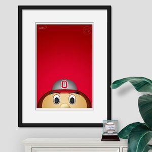 May include: A framed illustration of a cartoon mascot wearing a red and white baseball cap with a large "O" on the front. The mascot has brown hair, a brown face, and large eyes. The background is red.