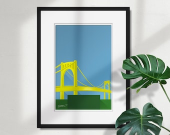 Op de afbeelding: Een ingelijste print van een gele brug tegen een blauwe lucht. De brug is een eenvoudige, gestileerde illustratie van een hangbrug. De print is in een zwarte lijst met een witte passe-partout.