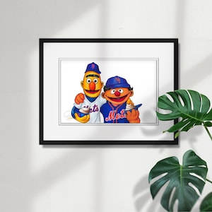 May include: Framed artwork featuring two cartoon characters in baseball uniforms. One character is wearing a Mets uniform and the other is wearing a Mets jersey. Both characters are holding ice cream cones. The artwork is framed in a black frame.