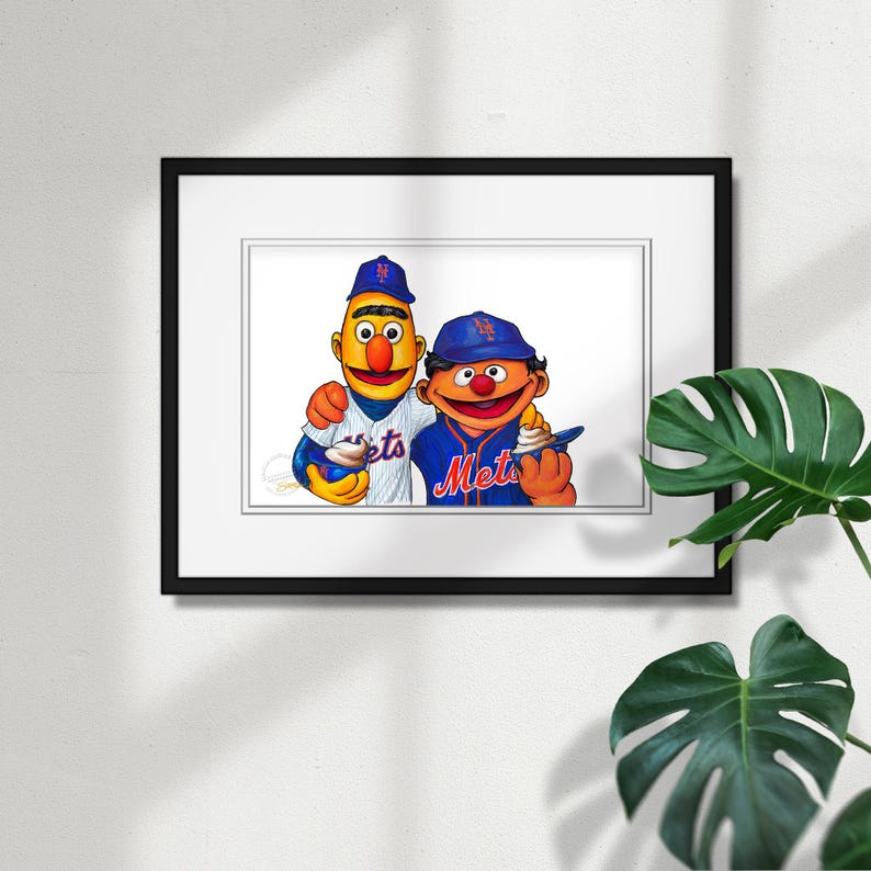 Puede incluir: Ilustraci&oacute;n enmarcada con dos personajes de dibujos animados con uniformes de b&eacute;isbol. Un personaje lleva un uniforme de los Mets y el otro una camiseta de los Mets. Ambos personajes sostienen un cucurucho de helado. La obra est&aacute; en un marco negro.
