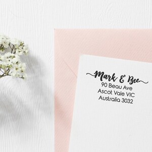 Op de afbeelding: Een witte envelop met een roze envelop erop. De witte envelop heeft een zwart retouradreslabel met de tekst "Mark & Bee, 90 Beau Ave, Ascot Vale VIC, Australi&euml; 3032."