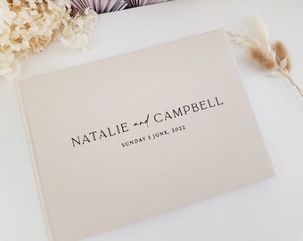 Puede incluir: Un libro de visitas de boda de color crema con el texto "NATALIE and CAMPBELL SUNDAY 5 JUNE, 2022" impreso en negro.
