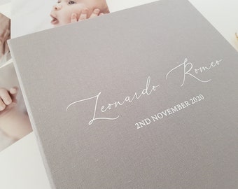 May include: A gray linen baby photo album with the name "Leonardo Romeo" and the date "2nd November 2020" printed in white.