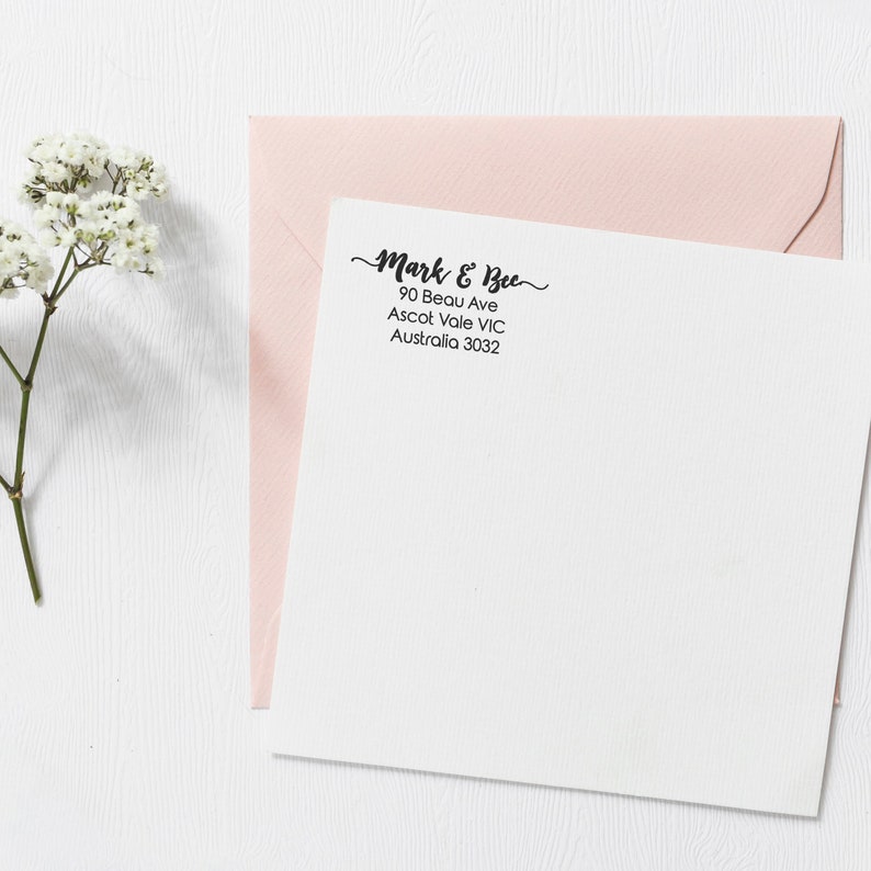Op de afbeelding: Een witte envelop met een roze envelop erop. De witte envelop heeft een zwart retouradreslabel met de tekst "Mark & Bee, 90 Beau Ave, Ascot Vale VIC, Australi&euml; 3032."