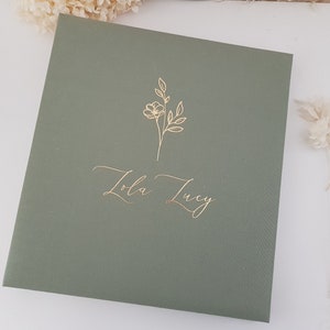 May include: A sage green cover with gold foil lettering that reads "Lola Lucy" and a simple gold floral design.