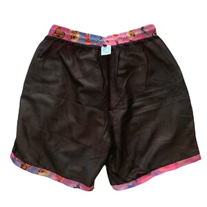 Pu&ograve; includere: Pantaloncini da bagno in rete nera con cintura a fantasia rosa, blu e bianca con farfalle e altri disegni.