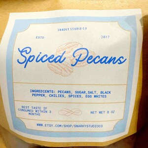 May include: A bag of spiced pecans with a label that reads "Spiced Pecans." The label lists ingredients and the net weight of 8 oz. The Etsy shop URL is also included.