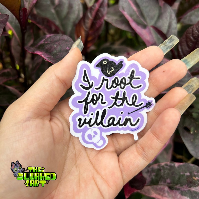 May include: Purple sticker with a black bird, arrow, and skull. The sticker says "I root for the villain".
