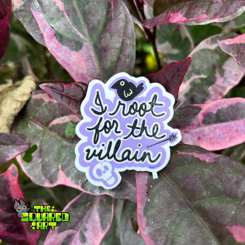 May include: Purple sticker with the text "I root for the villain" in black script. A black bird with a white eye is above the text. A small arrow and a skull are below the text.