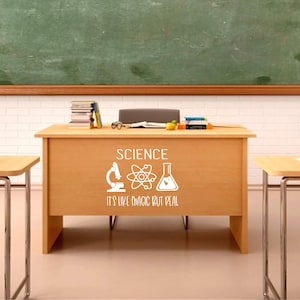 Peut inclure: Une scène de classe avec un bureau en bois orné du mot « SCIENCE » et d'icônes scientifiques. Le texte « IT'S LIKE MAGIC BUT REAL » est en dessous. Un tableau noir vert et d'autres bureaux sont visibles en arrière-plan.