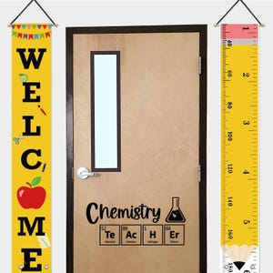 Peut inclure: Une porte de classe avec une bannière de bienvenue et une toise en forme de règle. La porte affiche le mot "Chimie" et des éléments du tableau périodique. La bannière de bienvenue est jaune avec du texte noir et des graphiques scolaires.