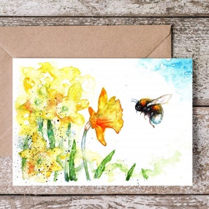May include: Watercolor painting of yellow daffodils and a bumblebee in flight. The flowers are in bloom and the bee is flying towards the daffodils.