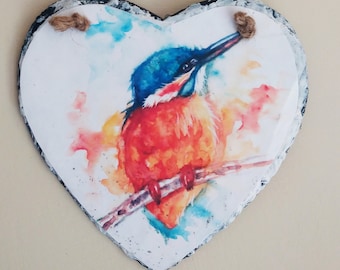 Puede incluir: Una pintura de acuarela de un martín pescador posado en una rama. El pájaro está pintado en tonos de azul, naranja y rojo, con un fondo blanco.