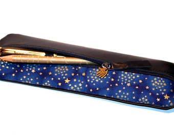 May include: A black leather pencil case with a zipper closure and a blue and gold star pattern lining. The zipper pull is a small gold hand.