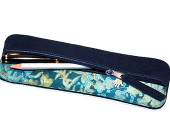 May include: A black zippered pencil case with a teal and gold floral lining. The case is open and a pen and pencil are inside.