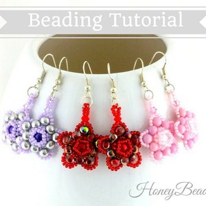 以下が含まれることがあります： 紫、赤、ピンクの3種類のビーズイヤリング。それぞれ星形のデザインで、花柄が施されています。イヤリングは白い台の上に置かれています。画像の右下に「HoneyBeads1」と書いてあります。