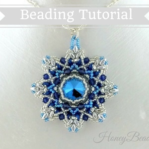 以下が含まれることがあります： 中央に大きな青いクリスタルをあしらった、青と銀のビーズでできた雪の結晶のペンダント。ペンダントは銀のチェーンからぶら下がっています。画像の右下には「Honey Beads」と書かれています。